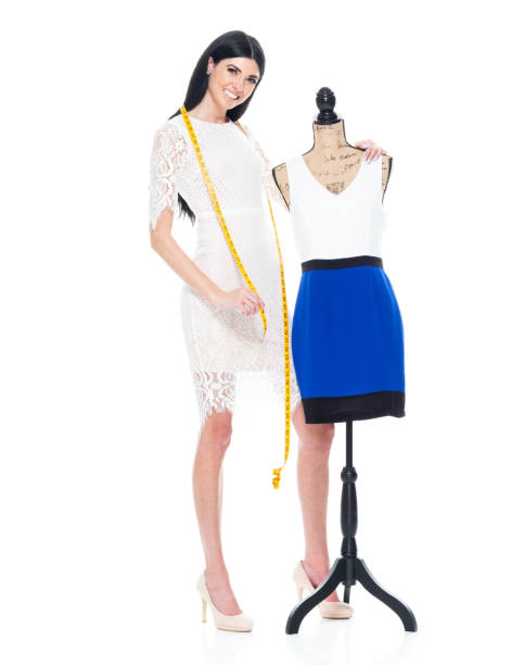 caucasian female owner sewing in front of white background in the clothing store wearing dress and using tape measure - tall human height women measuring imagens e fotografias de stock