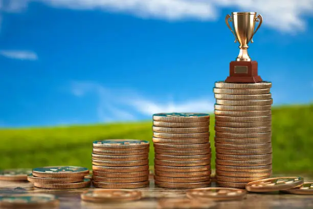 Photo of Trophy cup on stacks of coin.   Concept of success, growing business and profit.