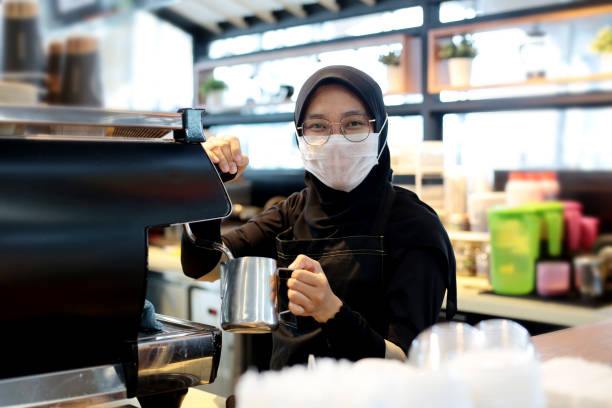 South East Asia: At The Airport A Muslim female adult is using coffee machine for preparing milk froth at airport cafe in Malaysia. klia airport stock pictures, royalty-free photos & images