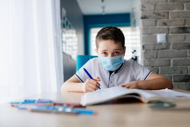 istock Child in protective medical mask doing his homework. School closed during coronavirus 1212404096