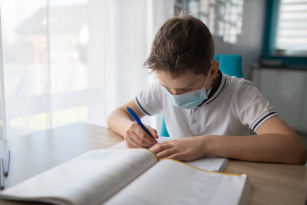 istock Child in protective medical mask doing his homework. School closed during coronavirus 1212404108