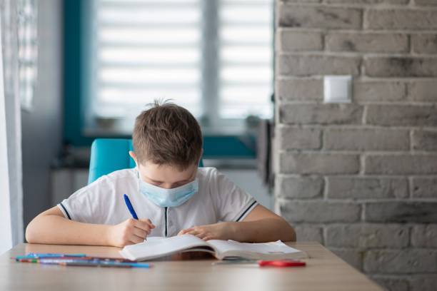 istock Child in protective medical mask doing his homework. School closed during coronavirus 1212404135
