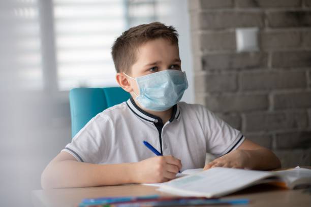 istock Child in protective medical mask doing his homework. School closed during coronavirus 1212404945