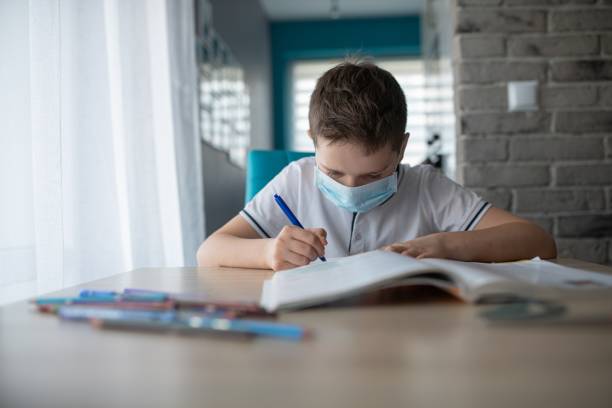 istock Child in protective medical mask doing his homework. School closed during coronavirus 1212404996