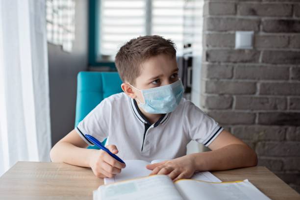 istock Child in protective medical mask doing his homework. School closed during coronavirus 1212405024