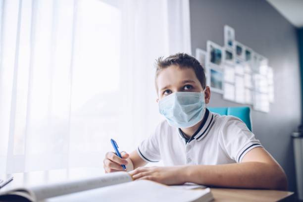 istock Child in protective medical mask doing his homework. School closed during coronavirus 1212405044