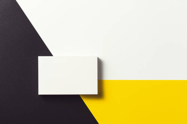 istock White business card on black, yellow and white background. 1212405735