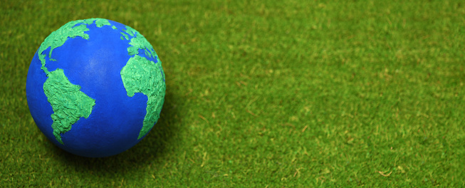 Background with handmade Earth model planet on grass background