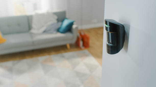 close up object shot of a modern movement detector unit on a white wall in a cozy apartment in the background. - motion sensor imagens e fotografias de stock