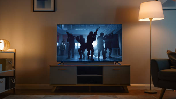 scatto di una tv con un film d'azione con soldati. è serale e la stanza a casa ha lampade funzionanti. - home movie foto e immagini stock