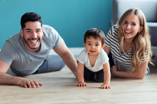 istock Pretty young parents looking at camera while playing with baby son at home. 1212406411