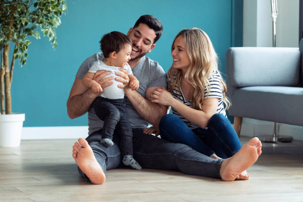 Pretty young parents playing with baby son while sitting on the floor at home. Shot of pretty young parents playing with baby son while sitting on the floor at home. 3 6 months stock pictures, royalty-free photos & images