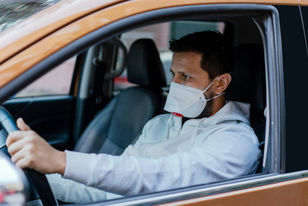 man driving his car with a protection mask in the city - illness mask pollution car imagens e fotografias de stock