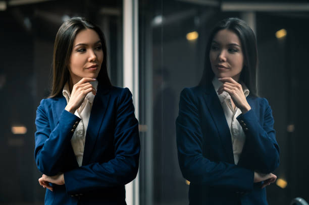The young asian businesswoman standing indoor The young asian businesswoman standing indoor looking in mirror stock pictures, royalty-free photos & images