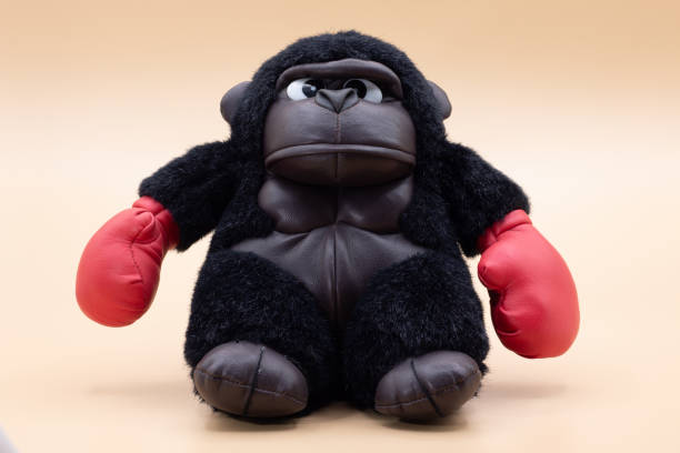 Stuffed toy gorilla boxer with angry face posing on a pale yellow background stock photo