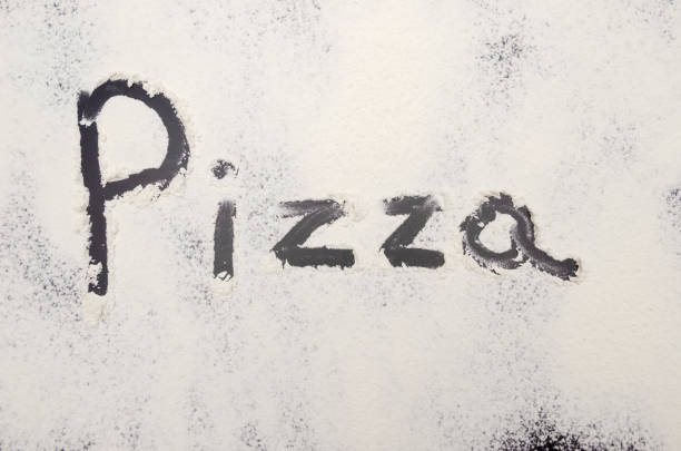 istock words Pizza written on a black background with flour. Inscription. 1212425850