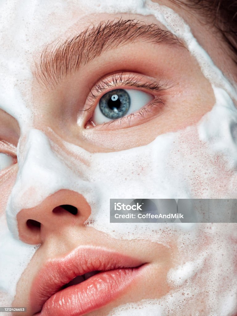 Beautiful woman applying cleaning foam on the skin Exfoliation Stock Photo