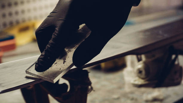 istock Ski maintenence. Removing excess wax from race ski base plastic scraper. Ski service and repair. Winter shop worker doing base repair. Rental workshop service. Repairman In Workshop Ski Service 1212430162