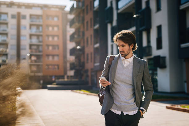 istock Young businessman text messaging on cell phone in the city. 1212431133