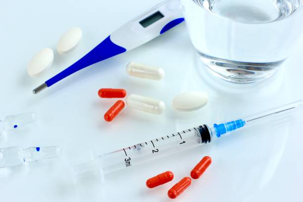 istock Multicolored pills, tablets against the virus, flu, disease, a thermometer and a syringe on light background. Medical concept of Virus Pandemic Protection, Coronavirus COVID-19. 1212435374