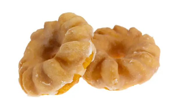 Side view of two glazed bite size crullers on a white background.