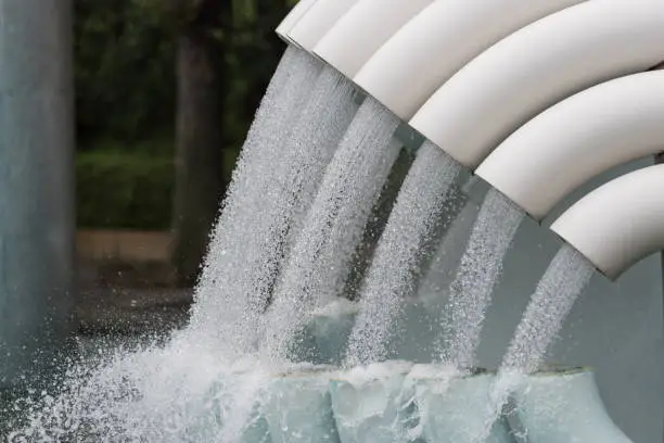 Water flowing from white tubes, pipes background.