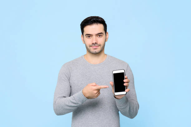 istock Young handsome man pointing to his mobile phone in hand isolated on light blue background 1212441252
