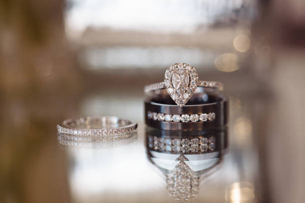 istock Wedding and engagement rings close up macro on reflective surface 1212444576