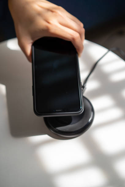 istock Woman putting her smartphone on wireless charger 1212476534