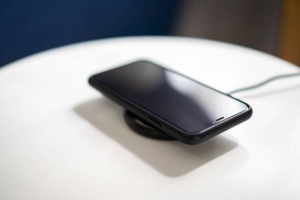 istock Smartphone charging with wireless charging matt on top of table 1212476759