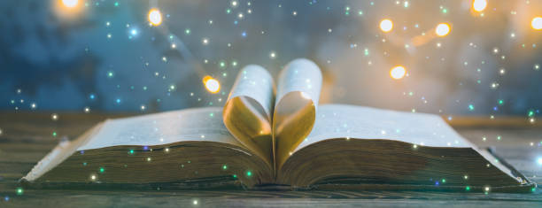 istock Old opened book, heart shaped paper sheets, dark background with stars toned vintage selective focus 1212483644