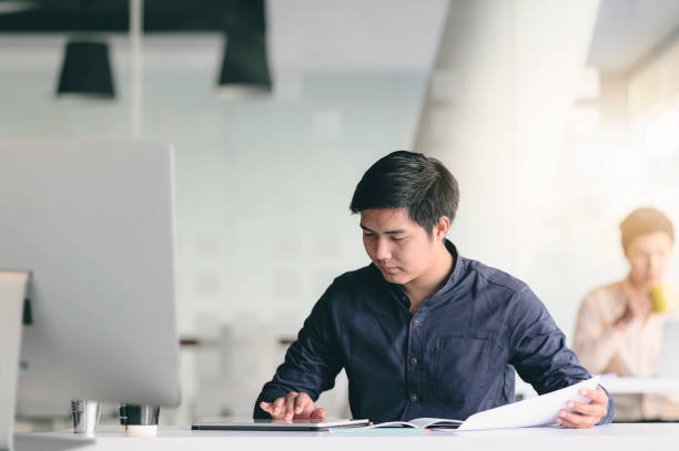 istock Young businessman working with tablet and paperwork  while sitting at office desk. 1212485611