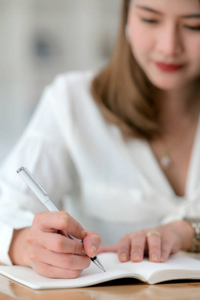 istock Closeup view of female hand with pen writing on diary. 1212486748