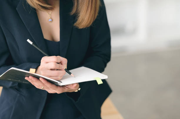 istock Closeup view of woman holding pencil writing on notebook 1212486829