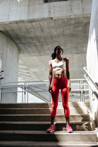 Portrait of pretty African woman athlete standing on staircase and looking at camera.