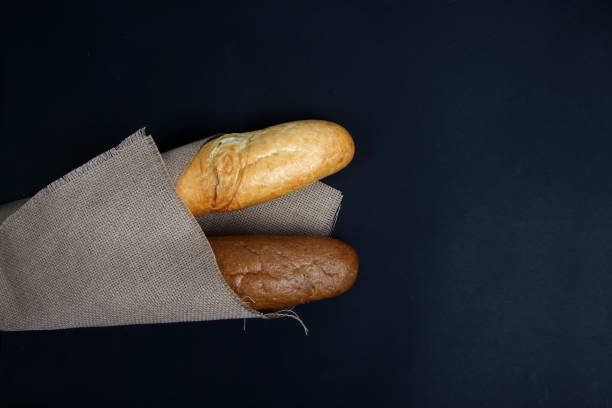 istock two baguettes wrapped in canvas on black background flat lay. Horizontal image 1212489014