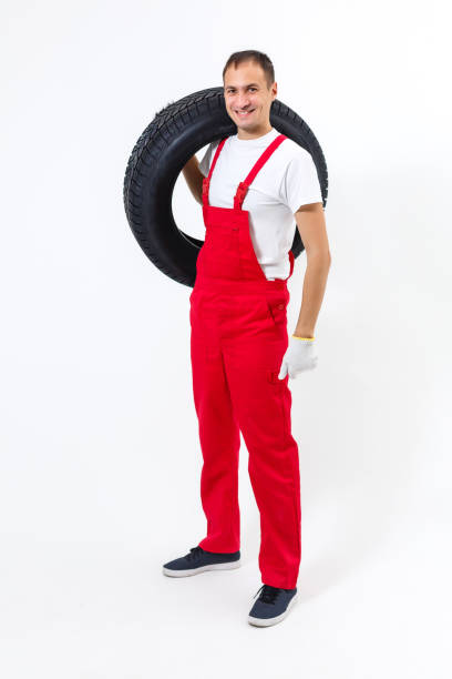 istock Mechanic carrying a tyre on a white background 1212491971