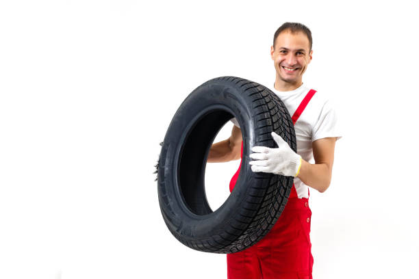 istock Mechanic carrying a tyre on a white background 1212492132