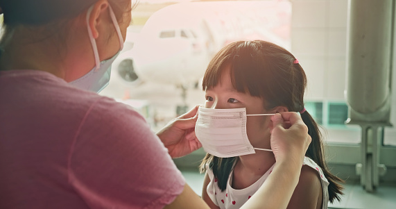 Asian parents wear masks to their children because of transmissible infectious diseases indoor in the airport