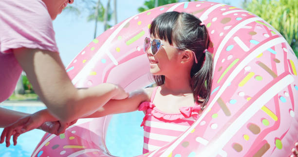 女の子の腕に日焼け止めを塗る - inflatable ring inflatable float swimming equipment ストックフォトと画像