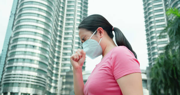 istock woman coughs and wears mask 1212494627