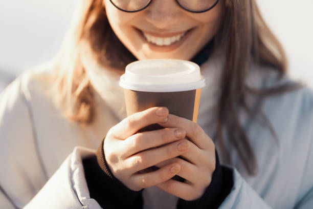 giovane donna adolescente felice che tiene una tazza di caffè da asporto - snow heat adult blond hair foto e immagini stock