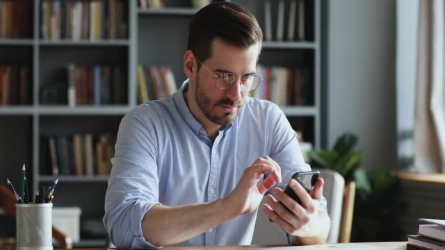 Professional businessman using modern smartphone texting message in office