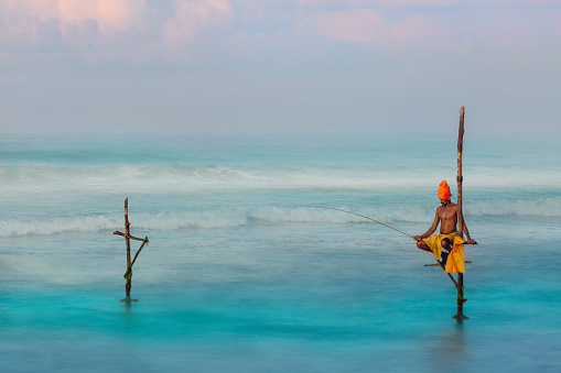 Weligama, Sri Lanka - April 1, 2019: Fisherman on the stilt at the sunrise, in Weligama, Sri Lanka