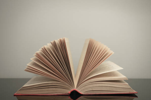 istock Beautiful open book on a gray and glass table background. 1212505494