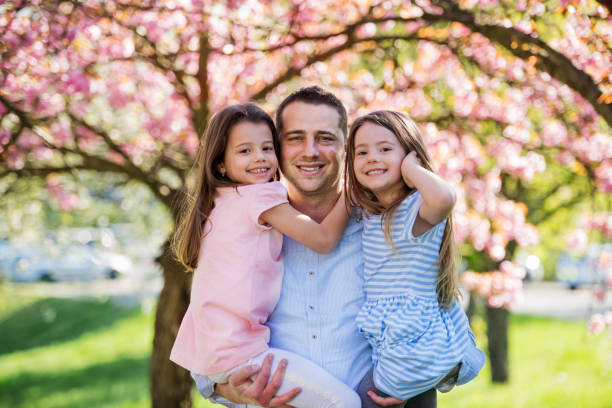 istock Young father holding small daughters outside in spring nature. 1212506024