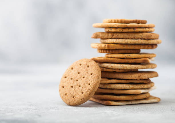 istock Stack of various organic crispy wheat, rye and corn flatbread crackers with sesame and salt on light kitchen table background. 1212507680