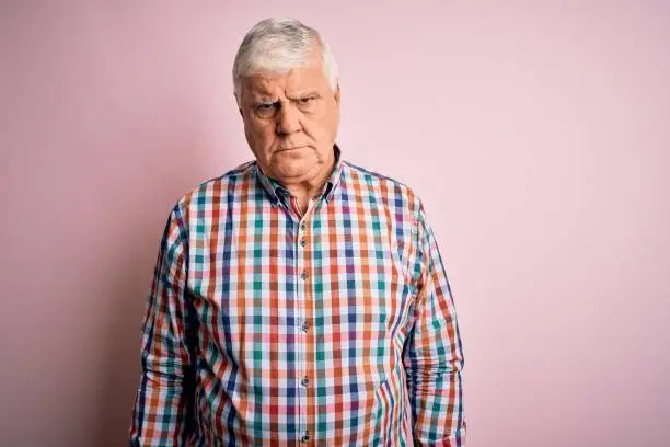 Photo of Senior handsome hoary man wearing casual colorful shirt over isolated pink background skeptic and nervous, frowning upset because of problem. Negative person.