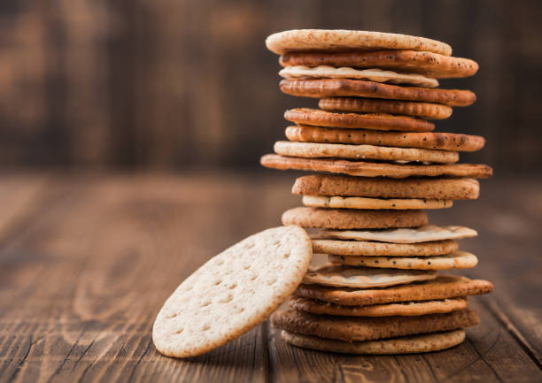istock Stack of various organic crispy wheat, rye and corn flatbread crackers with sesame and salt on wooden background. Space for text 1212509849