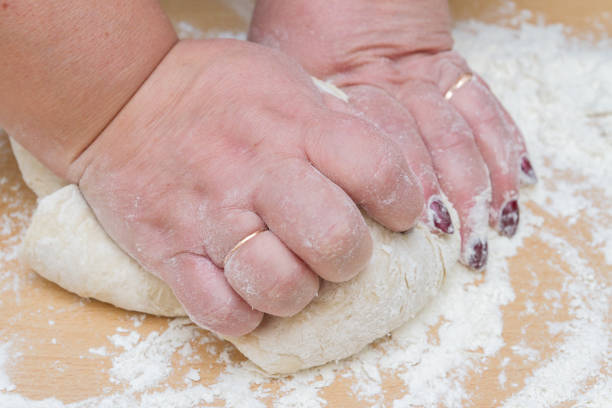 Kneading dough with flour on a wooden table at home